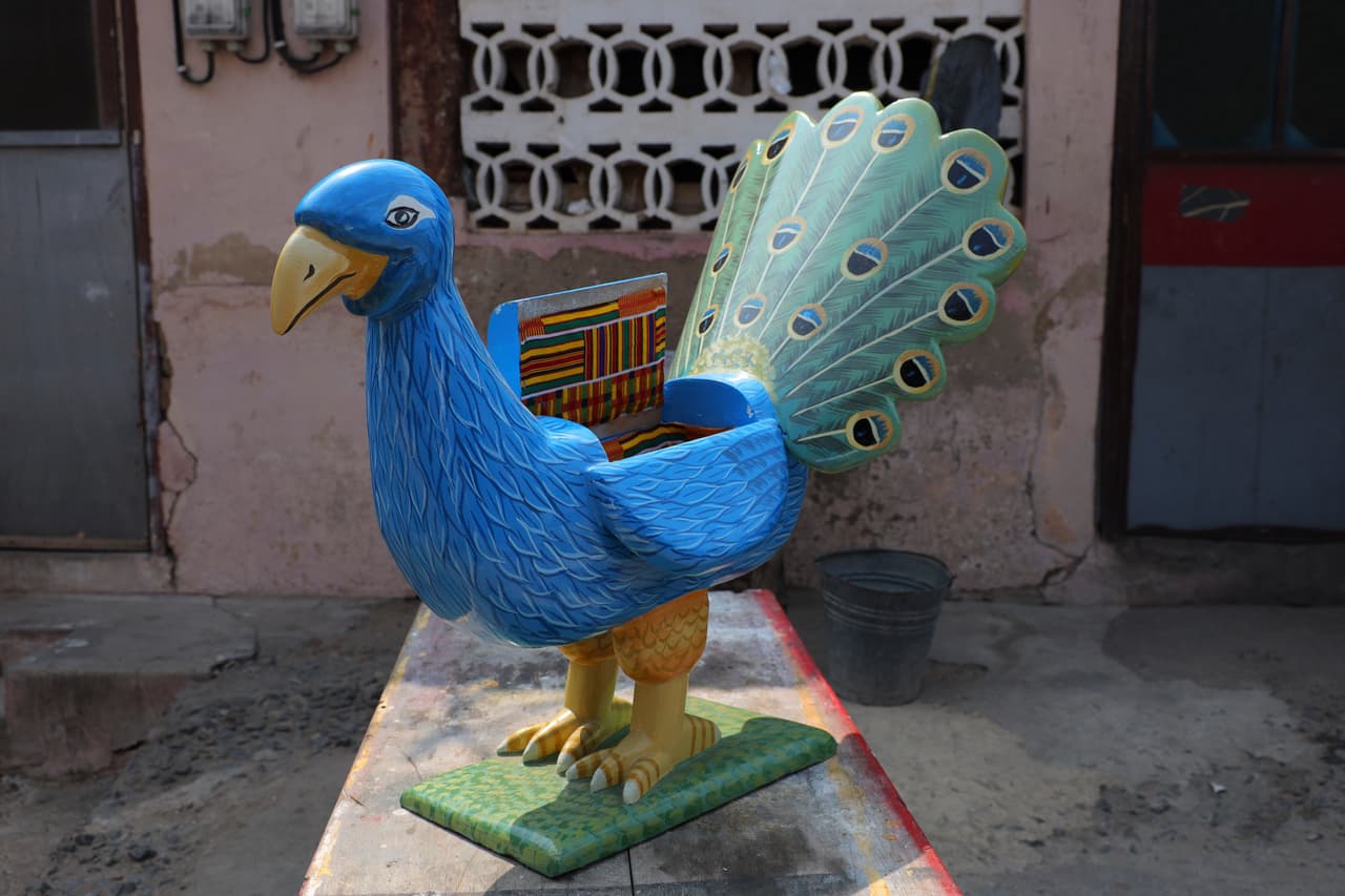 Un pavo real para una despedida extraordinaria: Un prototipo de ataúd de fantasía en miniatura con forma de pavo real se exhibe en el taller del artesano Nicholas Ablorh Annan, en Teshie. La pieza refleja el nivel de detalle y creatividad que caracteriza a esta particular artesanía funeraria.