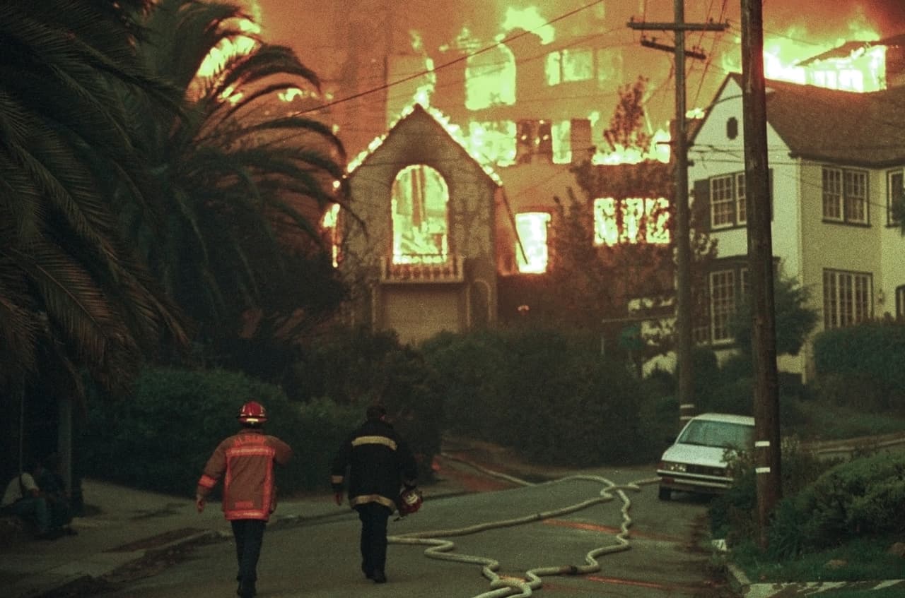 Bomberos avanzan sobre Rockridge Blvd. hacia algunas casas en llamas en Oakland.
<br>
<br>Un incendio de matorrales impulsado por el viento estalló en una tormenta de fuego cuando cercó vecindarios residenciales de lujo en las colinas de Oakland.