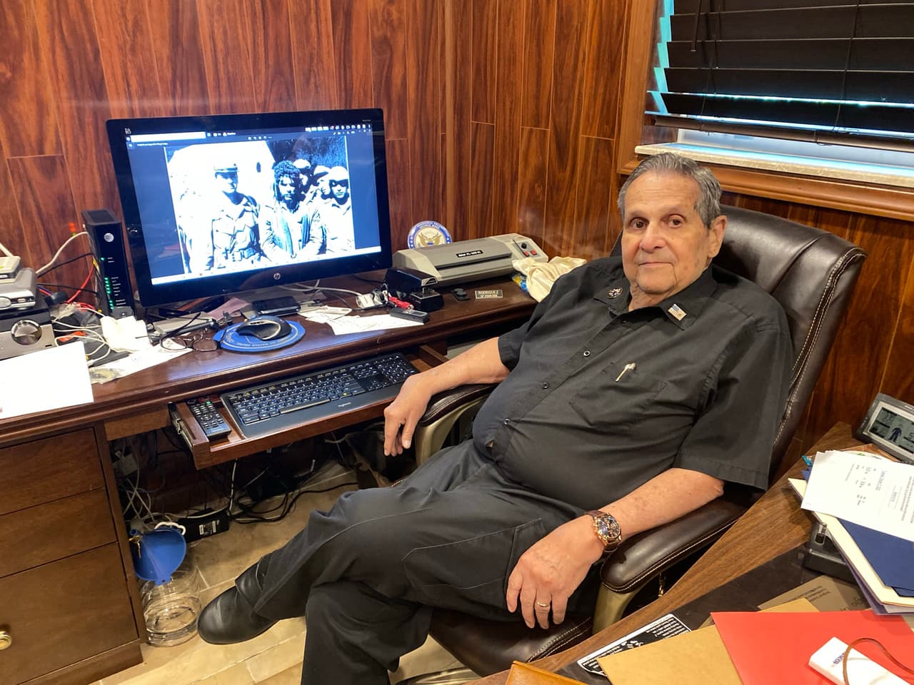 Félix Rodríguez en su casa de Miami, junto a la fotografía que lo muestra a un costado del líder guerrillero 'Che' Guevara el día de su captura en Bolivia en 1967.