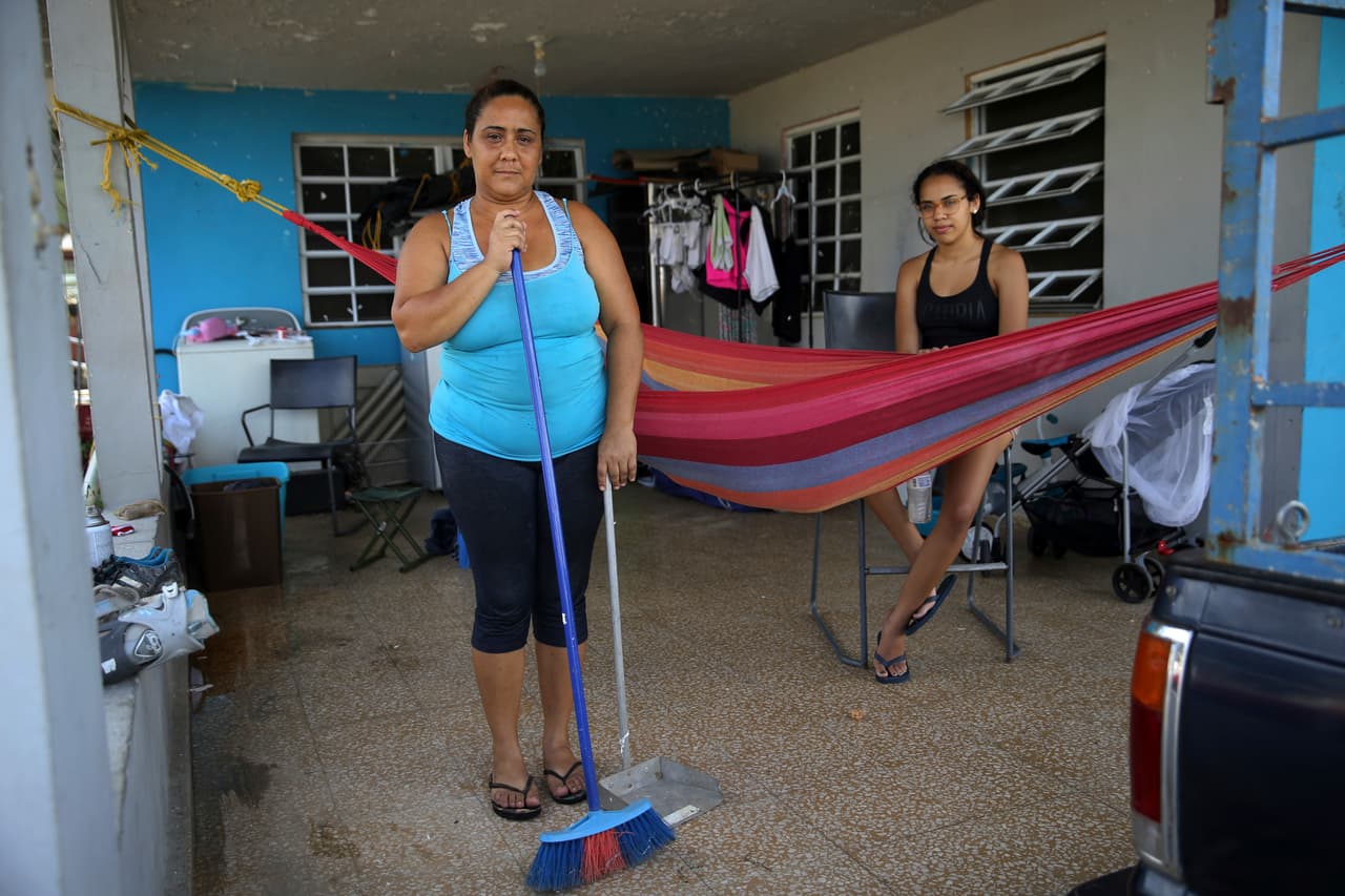 María Yuseno posa para un retrato con su hija Edmary Martínez mientras barre su cochera que contiene las pertenencias recuperadas de su casa dañada después del paso del Huracán María en Yabucoa, Puerto Rico. "La comida llega a los supermercados, pero se les acaba casi inmediatamente y los barcos no llegan", dijo Yuseno.
<br>
