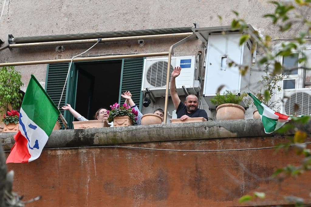 En Italia, las personas saludan y aplauden durante "Un applauso per l'Italia" (Un aplauso para Italia) en el distrito de Garbatella en Roma. Desde hace días una serie de decretos del gobierno italiano limitan drásticamente los movimientos de los ciudadanos, con amplios sectores de la economía cerrados.