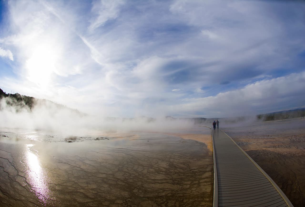 Turistas pasean cerca del Geyser Midway en el Parque Nacional Yellowstone en Wyoming. Yellowstone, que protege 10,000 géiseres y aguas termales, es el primer parque nacional de Estados Unidos. Fundada en 1872, Yellowstone se extiende a través de Wyoming, Montana y Idaho. El nombre del parque se deriva del río Yellowstone, que atraviesa la tierra.