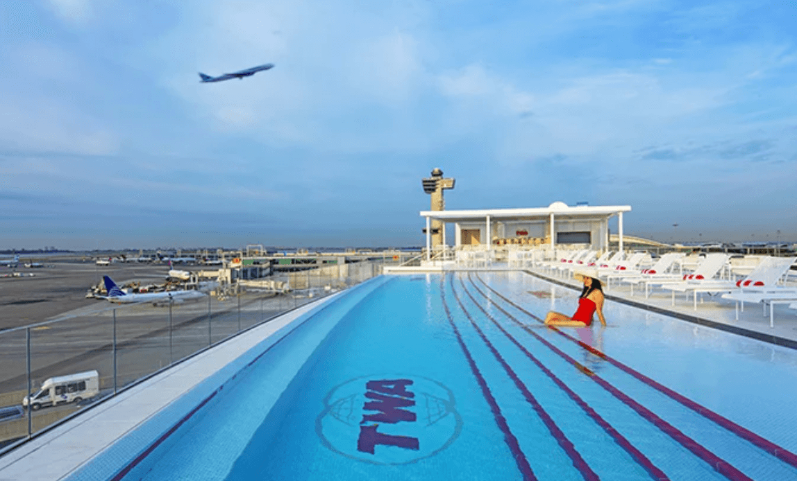 <b>TWA Hotel</b>
<br>Uno Idlewild Drive
<br>Aeropuerto Internacional JFK
<br>Queens, Nueva York
<br>
<a href="https://www.google.com/search?q=twa+hotel+address&rlz=1C5GCEM_enUS990US990&oq=twa+hotel+address&aqs=chrome.0.0i457i512j46i20i175i199i263i512j0i512l5j0i10i512j0i512.3160j0j4&sourceid=chrome&ie=UTF-8">(212) 806-9000</a>
<br>
<br>
<b>Esta piscina infinita </b>(con el agua al nivel de sus muros para que se desborde) es toda una piscina ‘de altura’ pues queda en la azotea del TWA Hotel. Y, como está en el aeropuerto JFK, desde ella puedes disfrutar de las emocionantes vistas de la pista 4 izquierda/22 derecha de JFK.
<br>
<br>Pero ni te creas que tienes que hospedarte en el hotel para nadar en ella: acepta reservaciones a partir de las 11h y sus precios son asequibles: $25 de lunes a jueves y $50 de viernes a domingo. Las reservaciones se hacen en: poolbar@twahotel.com y duran solo 1.45 horas.
<br>