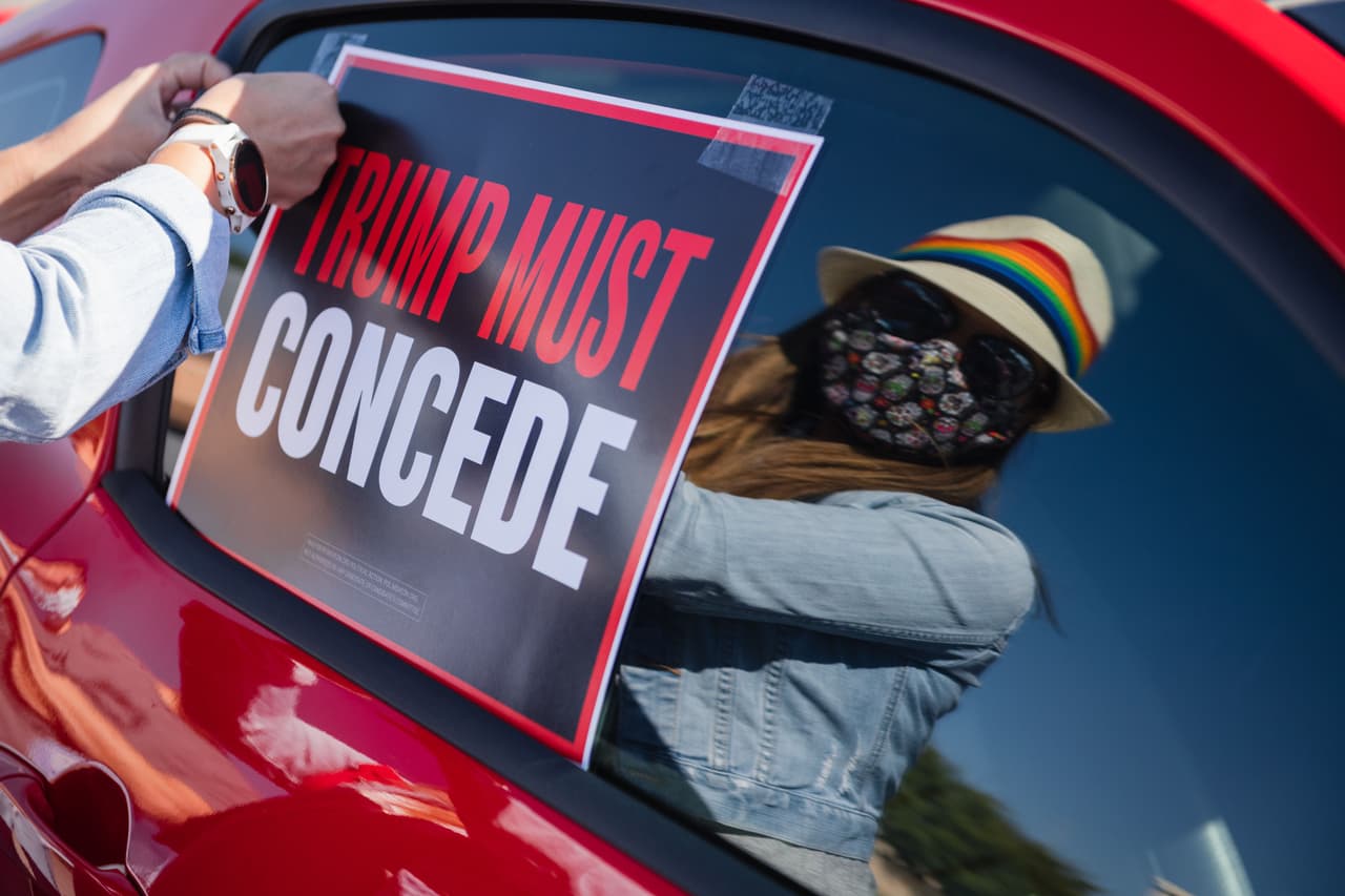 Una mujer pone un letrero que dice "Trump debe aceptar [la derrota]" en una caravana a favor del presidente electo Joe Biden en El Paso, Texas, convocada este sábado.