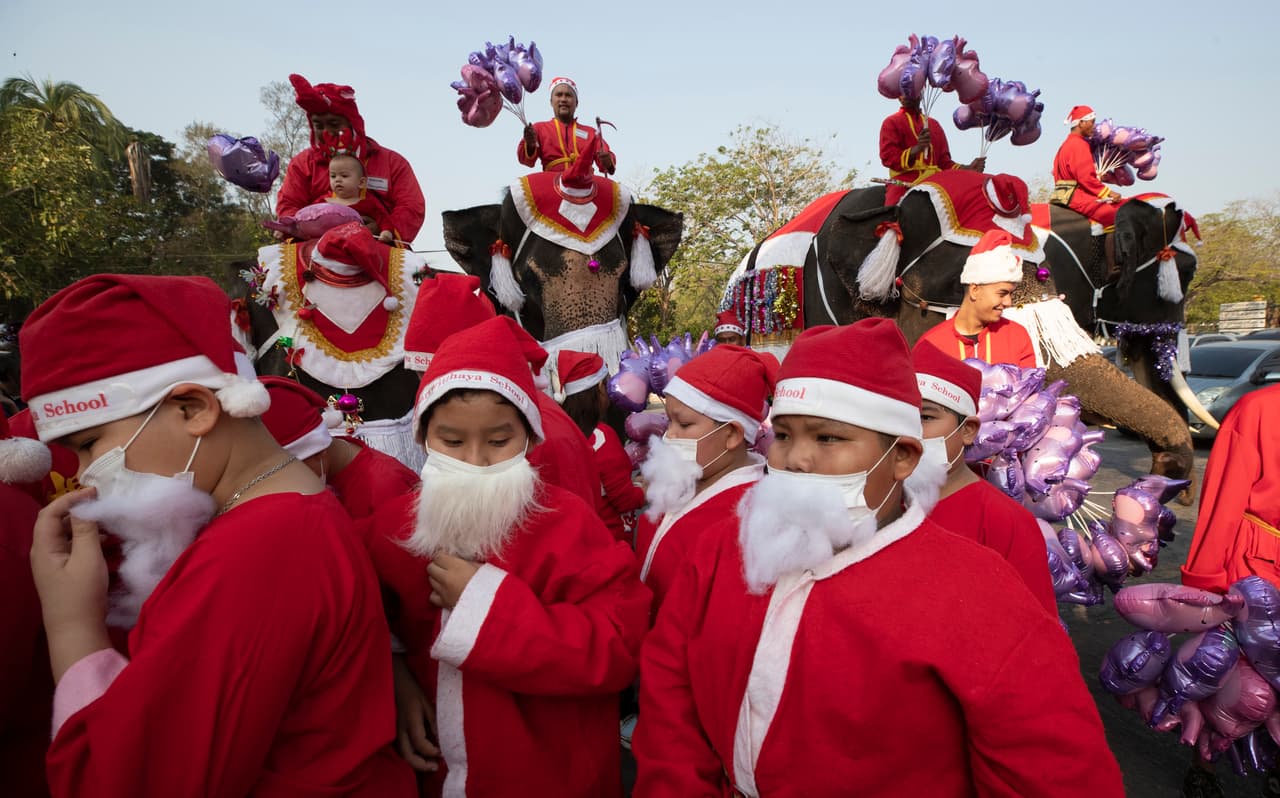 Estudiantes y elefantes vestidos con trajes de Santa Claus reparten regalos en una escuela al norte de Bangkok, Tailandia. 23 de diciembre de 2019.