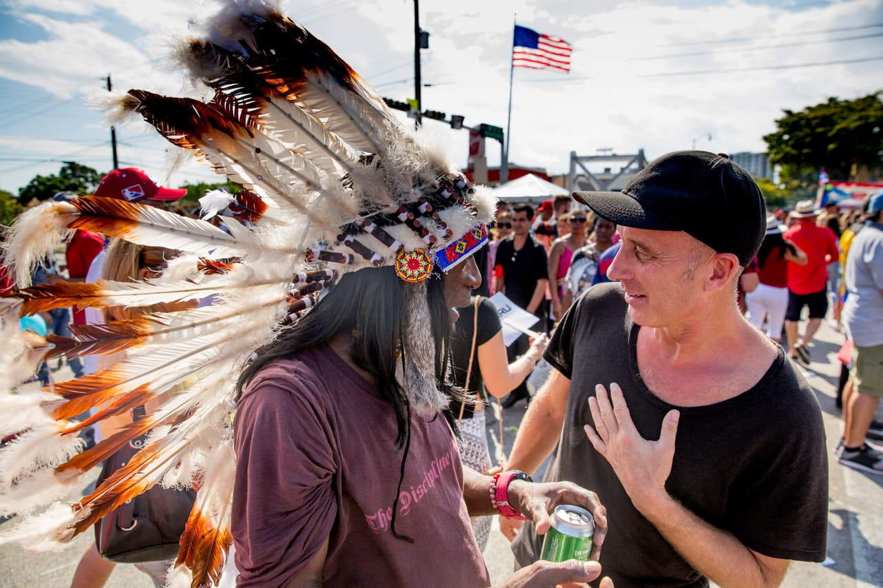 Un hombre con un penacho de indio americano saluda a los que caminan por en el carnaval de la calle Ocho.