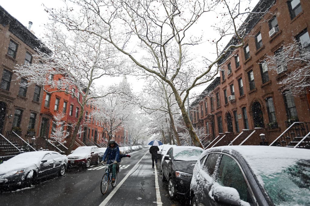 NEW YORK, NEW YORK - DECEMBER 09: A man ride his bikes past a person walking in street as it snows on December 09, 2017 in the Carrol Gardens neighborhood of the Brooklyn borough of New York City. The area is expected to see 3-6 inches of snow in the first snowfall of the season. (Photo by Michael Heiman/Getty Images)