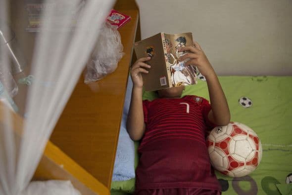Un niño lee mientras descansa tras un duro entrenamiento.