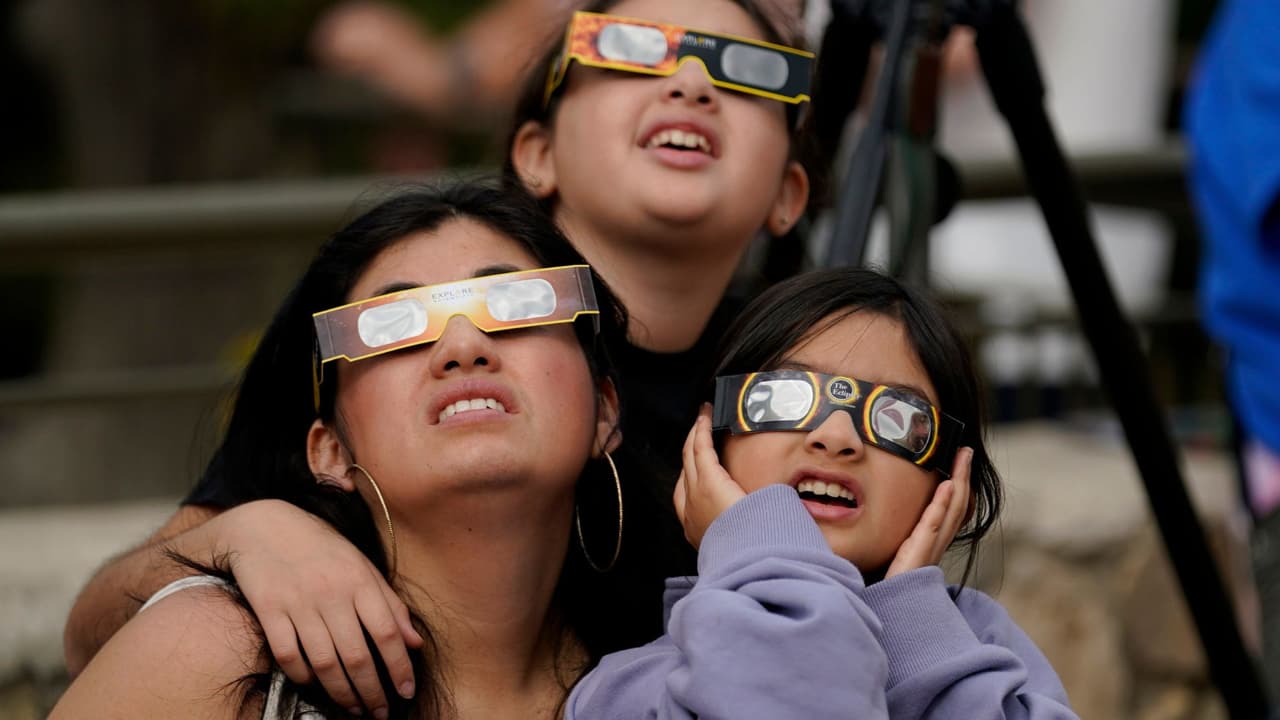 Las personas utilizan gafas especiales para ver cómo la Luna se mueve delante del Sol durante un eclipse solar anular, o anillo de fuego, el sábado 14 de octubre de 2023, visto desde San Antonio, Texas.