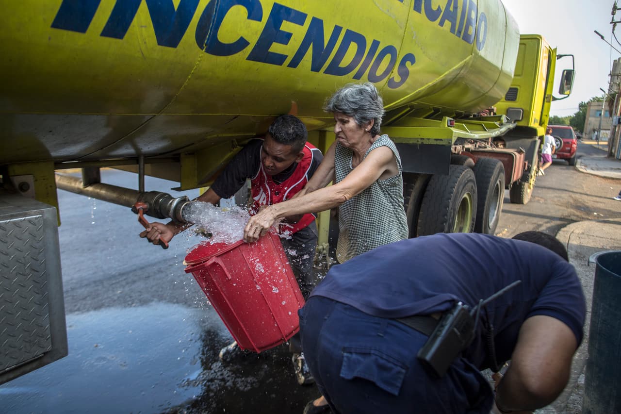Una mujer llena un cubo de agua potable en un camión cisterna durante los cortes de agua provocados por la falta de electricidad. La oposición culpa de la miseria a las erróneas políticas económicas, la mala gestión y la corrupción del gobierno socialista instaurado por el fallecido Hugo Chávez.