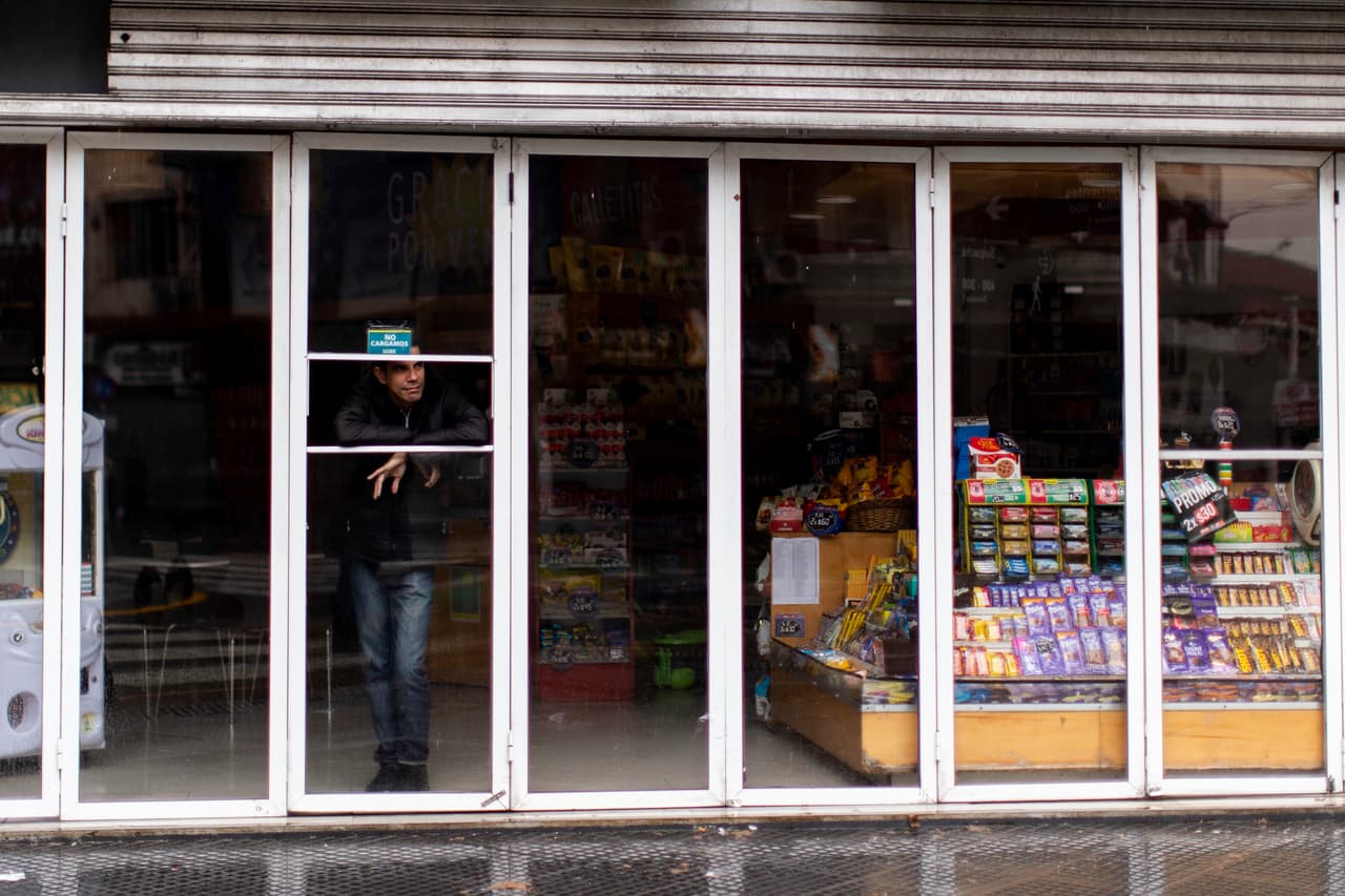 Un hombre espera dentro de una tienda de abarrotes sin luz que se encuentra cerrada durante el megacorte de energía en Buenos Aires.