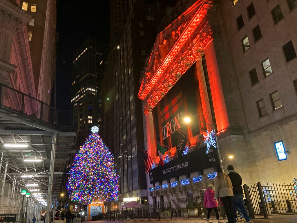 Un árbol de navidad frente a la sede de la Bolsa de Nueva York, decorada con luces rojas.