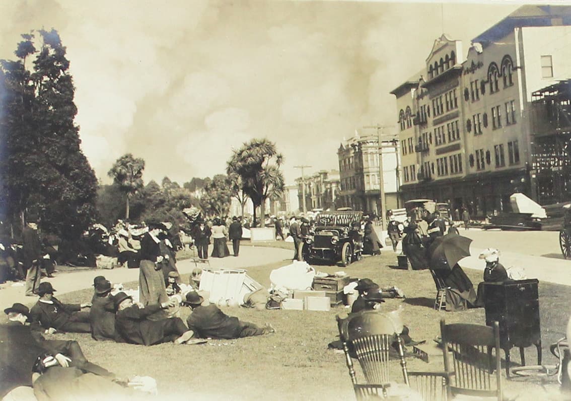 Personas desalojadas descansan sobre la grama de un parque.