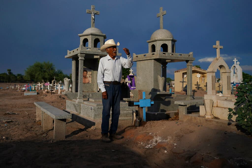 Guillermo Rojo, padre del líder asesinado Tomás Rojo, reza junto a la tumba de su hijo, adornada con una cruz azul.