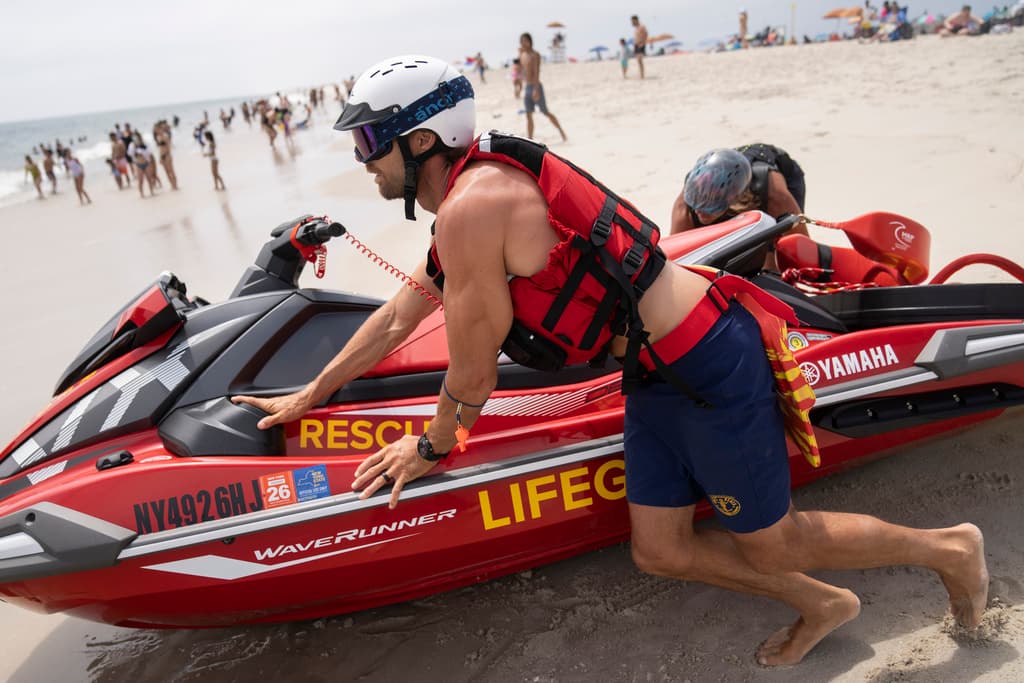 Salvavidas lanzan una moto de agua para una patrulla de tiburones en el Parque Estatal Jones Beach.