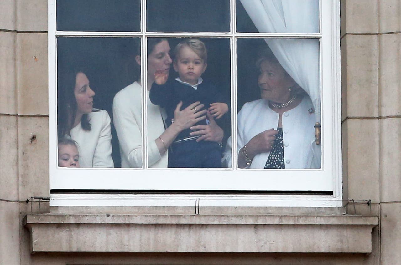 El príncipe George de Cambridge es cuidado por su niñera Maria Teresa Turrion Borrallo, mientras él agita la mano a través de la ventana del palacio de Buckingham, afuera se desarrolla la ceremonia del color el 13 de junio de 2015 en Londres.