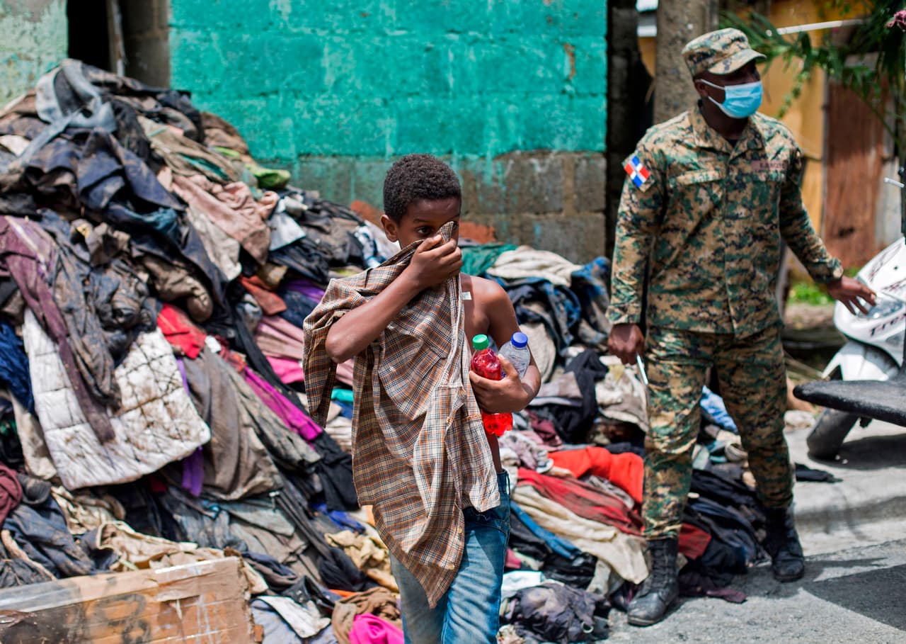 Un chico camina por una calle pasando una pila de pertenencias dañadas en Hato Mayor.