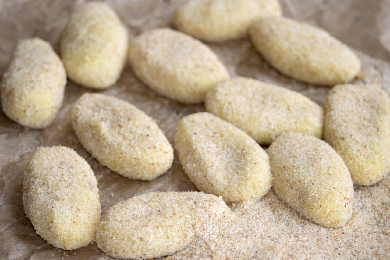 Rueda las croquetas sobre la harina hasta cubrirlas ligeramente, después pásalas por la mezcla de huevo y al final por el pan molido.