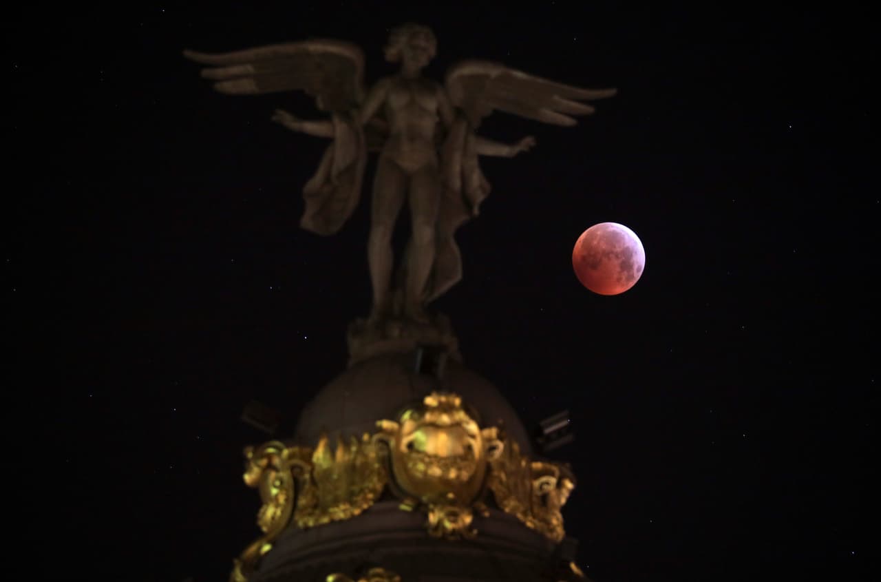 Una espectacular imagen nítida de la súper luna de sangre en el cielo de Madrid, detrás de la estatua de la Victoria Alada.
