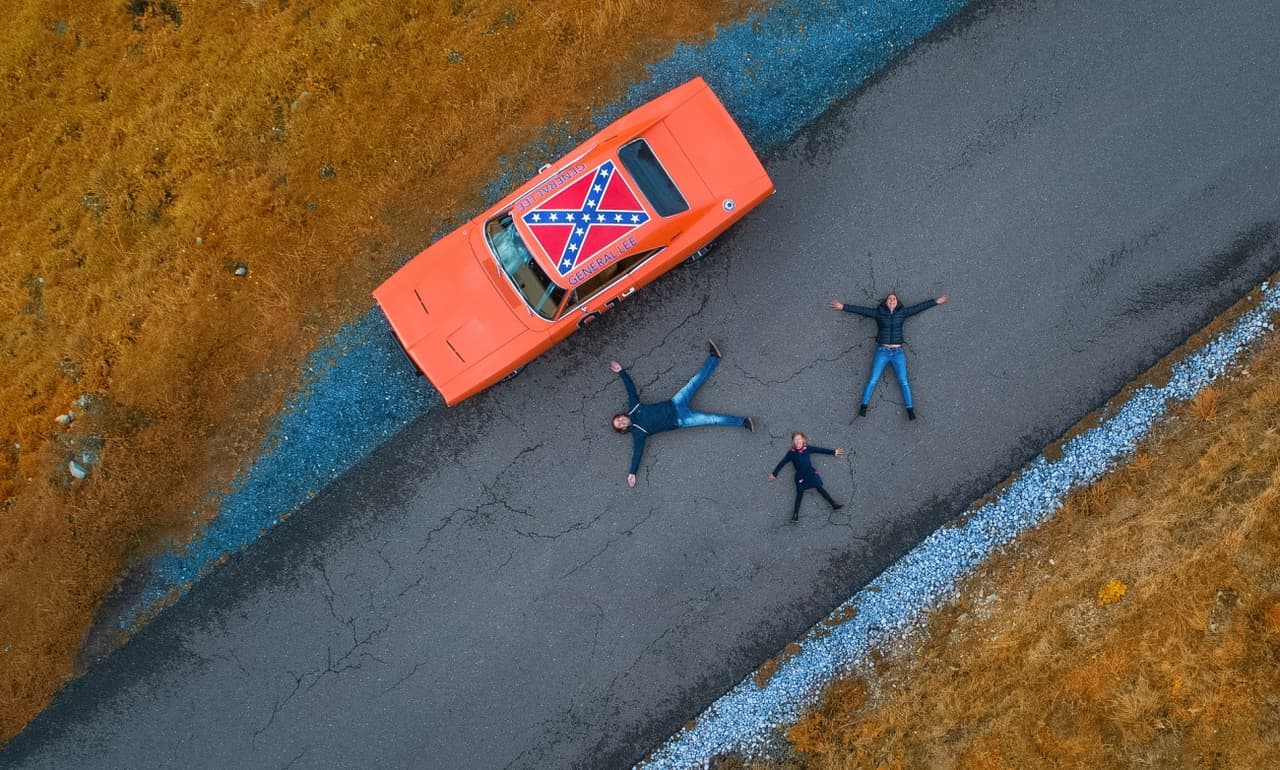'X' una imagen que 
<b>muestra a una familia recostados sobre una carretera</b> a lado de su auto y lo que parece ser una bandera confederada.