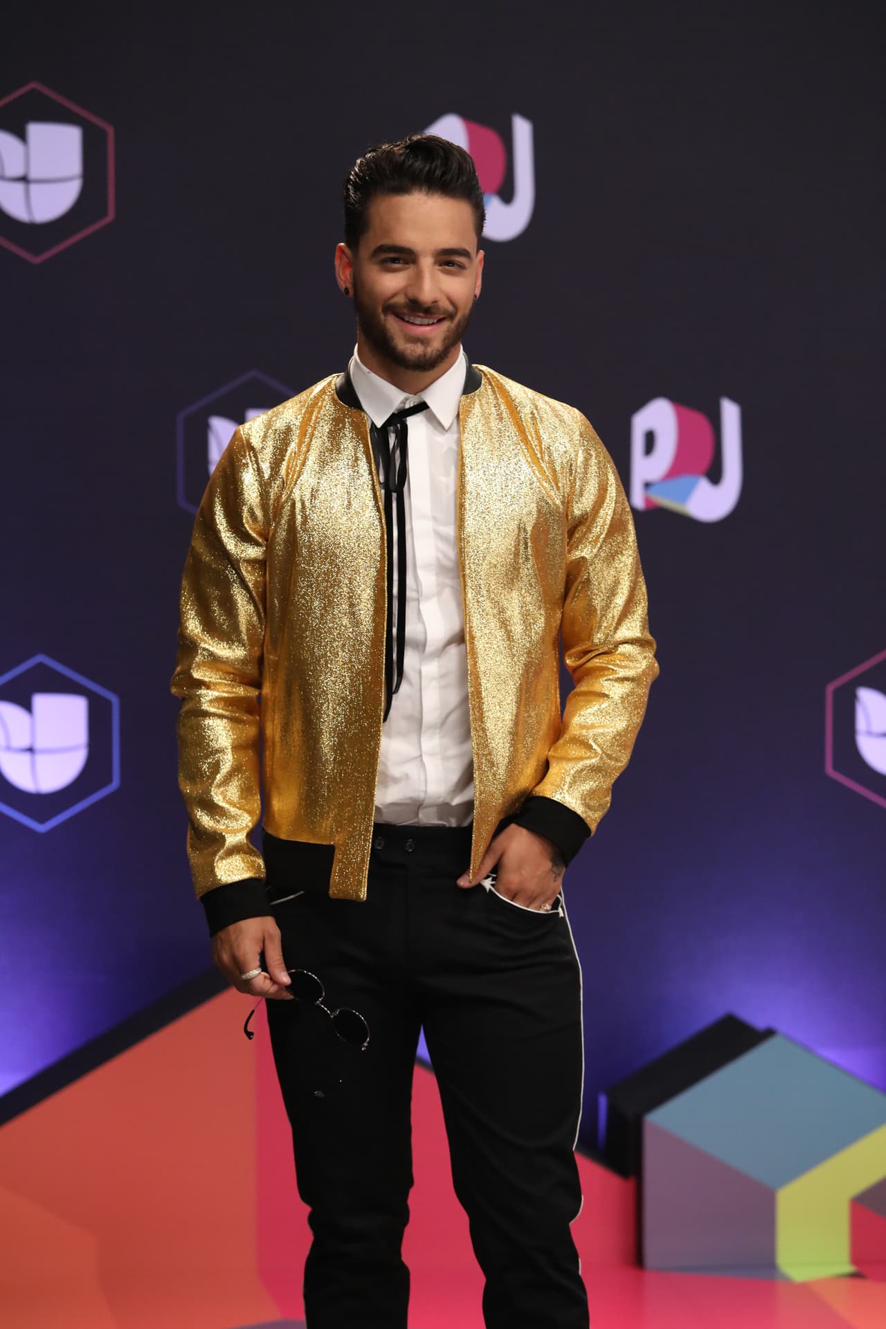 Maluma se presentó con una cazadora bomber dorada y unos pantalones negros.