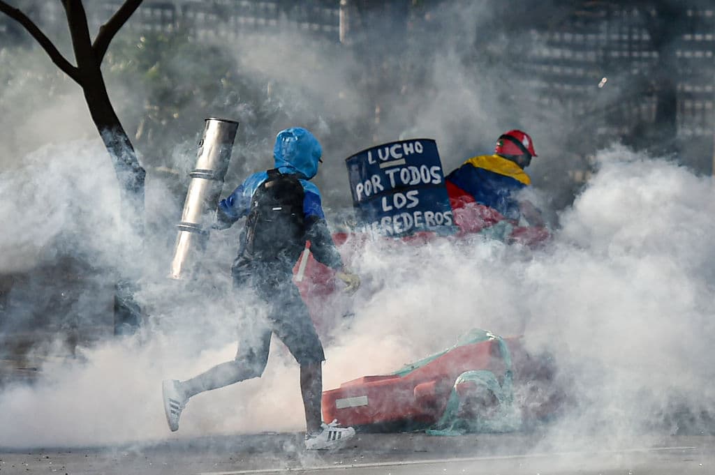 Tear gas rises around demonstrators as they clash with riot police officers during a protest against the government of Colombian President Ivan Duque, in Cali, Colombia, on May 22, 2021.