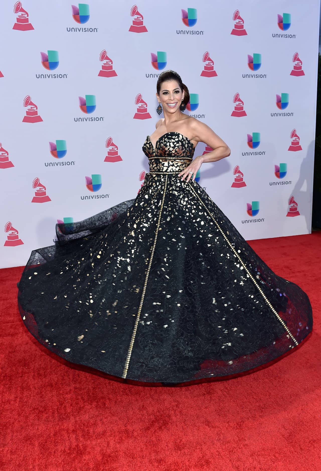 Lourdes Stephen, llegó súper elegante en este gran vestido negro con aplicaciones doradas.