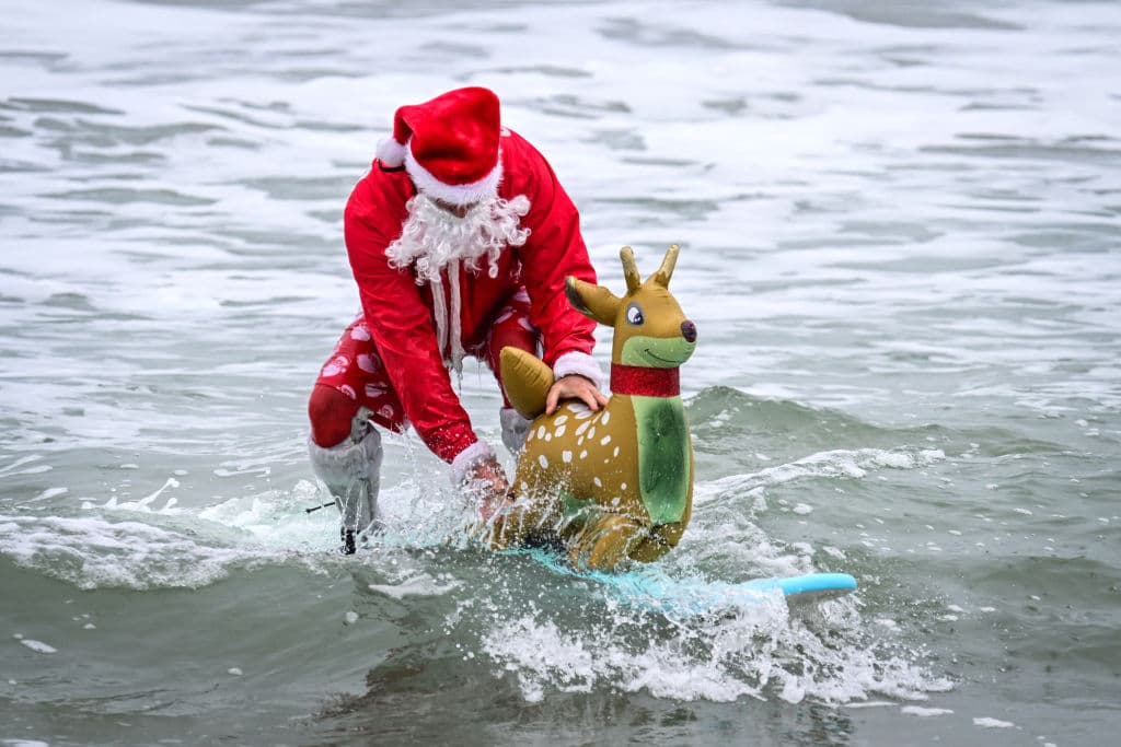 En Cocoa Beach, 59 millas al sureste de Orlando, hace 16 años que Santa Claus no llega en trineo, sino en tablas de surf, con todo y renos, como parte del evento benéfico 'Surfing Santas'.