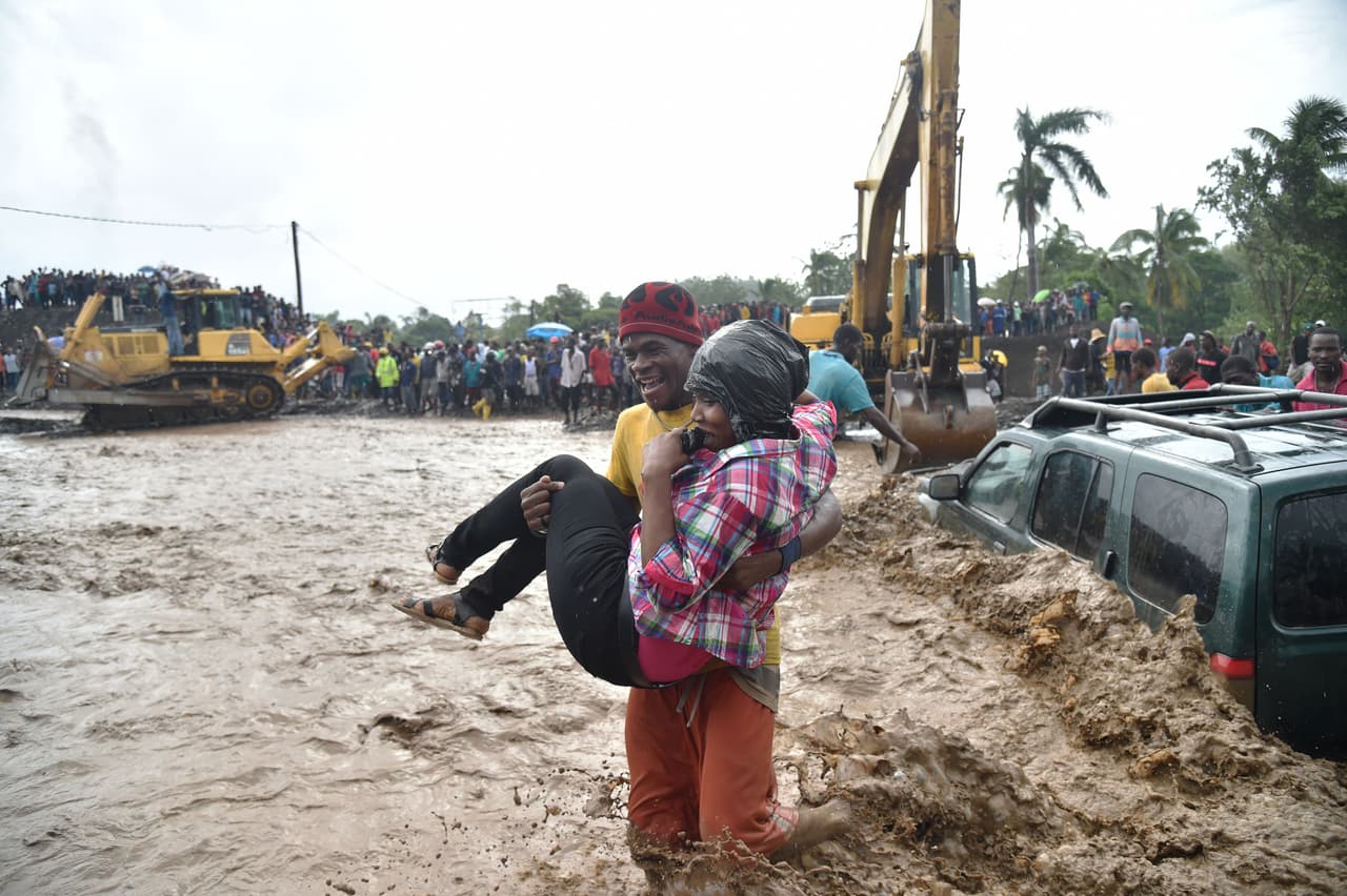 Un hombre lleva a una mujer en sus brazos a través del río La Digue en Petit Goave cuando un puente fue arrastrado durante el huracán Matthew, cortando el transporte por carretera a la península suroeste.