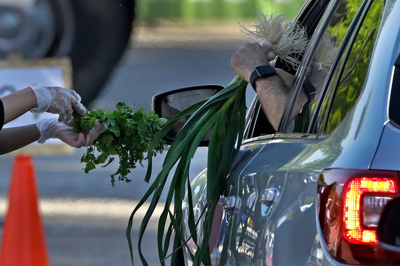 <b>Mercados de agricultores.</b> Un vendedor entrega sus productos a un cliente por la ventana de su auto, en un mercado de agricultores de Overland Park, Kansas. 2 de mayo. En todo el país los programas de ayuda alimentaria han utilizado también este sistema.