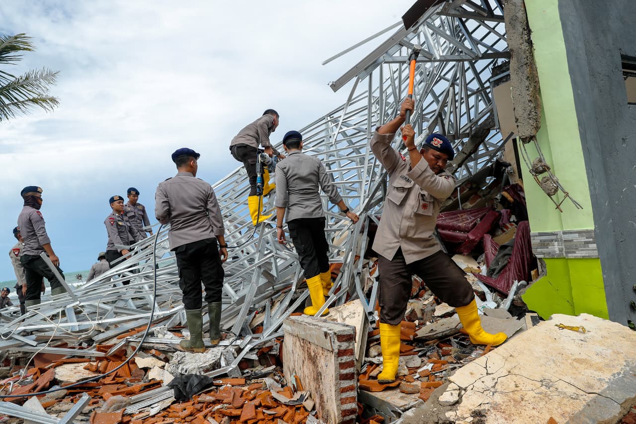 Oficiales de la policía destrozan estructuras de un hotel afectado por el tsunami, en búsqueda de sobrevivientes o cuerpos.