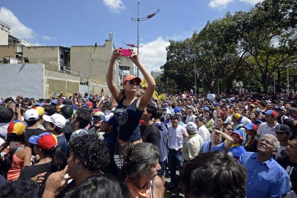 Un manifestante desarmado toma fotos de lo que está sucediendo. Los estudiantes llevaron a cabo una manifestación pacífica contra el régimen del mandatario Nicolás Maduro el 12 de febrero de 2014. Motorizados uniformados y con sus caras cubiertas, dispararon contra los manifestantes, matando a dos estudiantes y a un oficial.