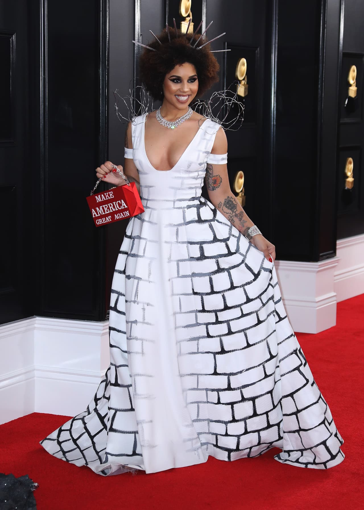En la alfombra roja, delante de los fotógrafos,
<b><a href="https://www.univision.com/noticias/acoso-sexual/la-cantante-joy-villa-conocida-por-su-apoyo-a-trump-denuncia-a-un-exasesor-del-presidente-por-acoso-sexual"> Villa</a></b> se retiró la tela que recubría su vestido y dejó ver su look de la noche, un traje blanco estampado con los dibujos de unos ladrillos.