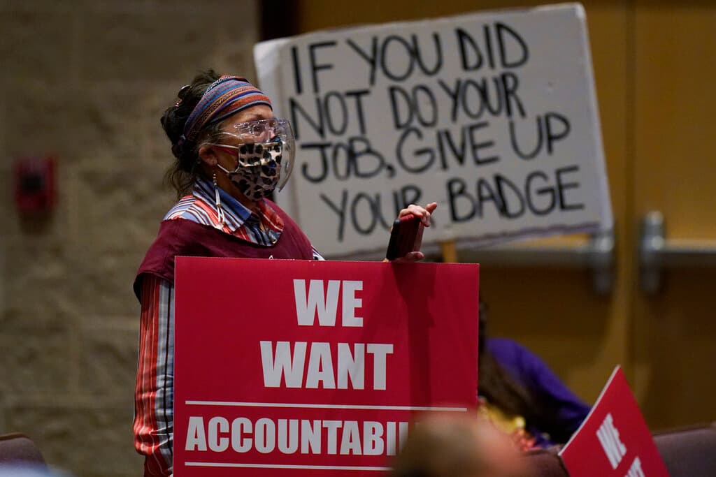 Padres y familiares sostienen carteles en la reunión de la Junta Directiva.