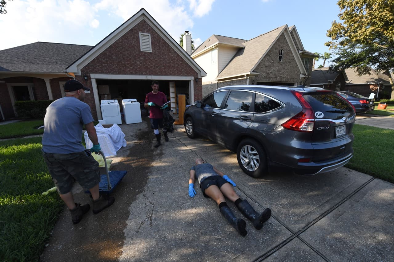 Cansado de cargar objetos fuera de la casa, un miembro de la familia Olson toma un descanso del trabajo de recuperación del hogar de su padre, en Twin Oaks, un vecindario de Houston.