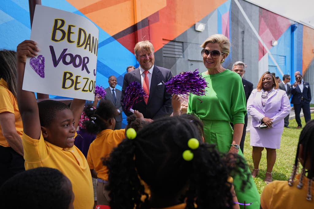 Un estudiante sostiene una pancarta con el mensaje "Gracias por visitarnos" escrito en holandés.