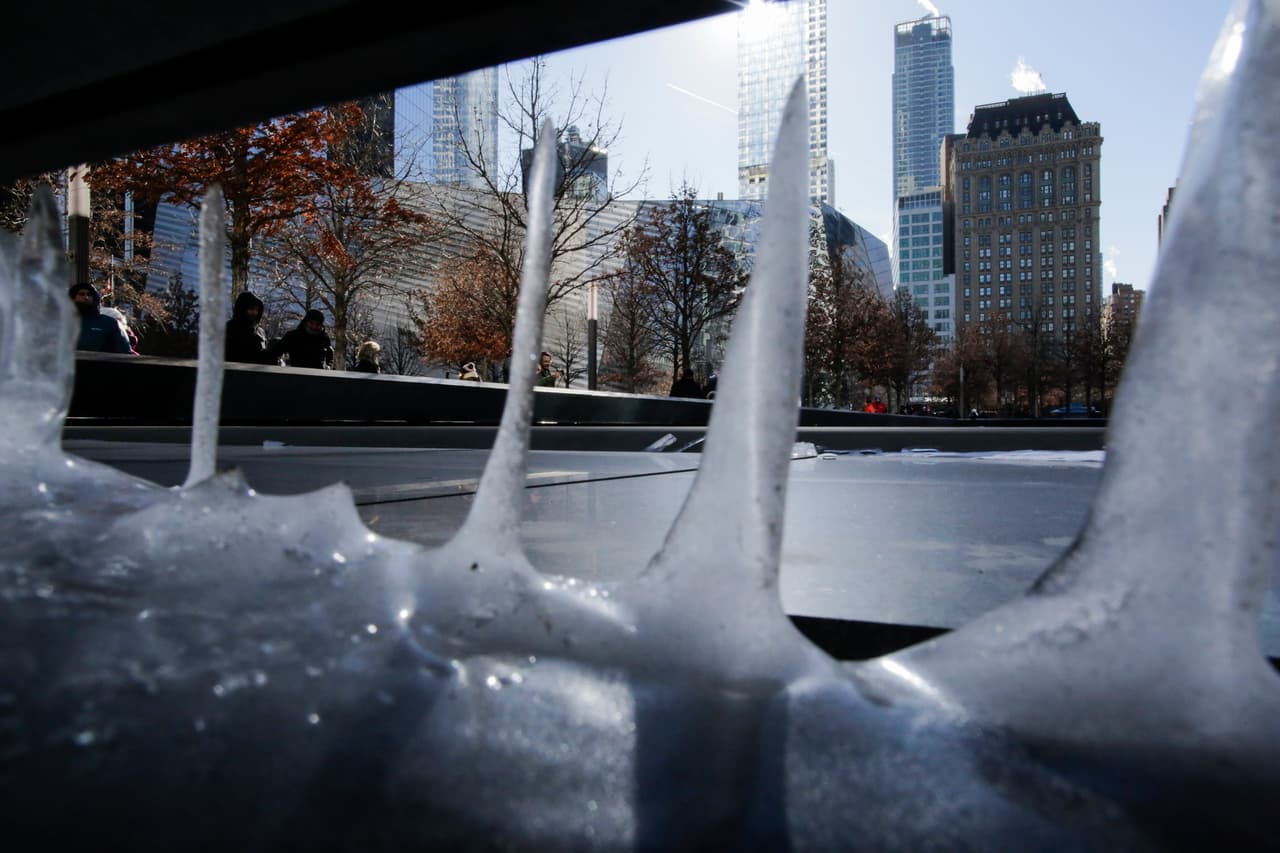 Un grupo de turistas visita el monumento a las víctimas de los atentados del 11 de septiembre de 2001 en Nueva York, soportando temperaturas bajo cero el 7 de enero de 2018.