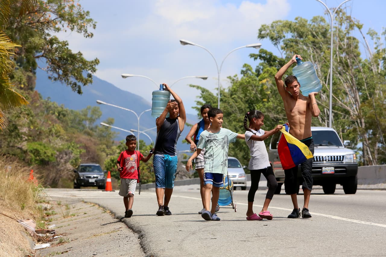 Residentes de Caracas caminan por una autopista que bordea la montaña El Ávila, de cuyos arroyos sacan el agua potable, debido a la escasez generada por el apagón de más de cuatro días.