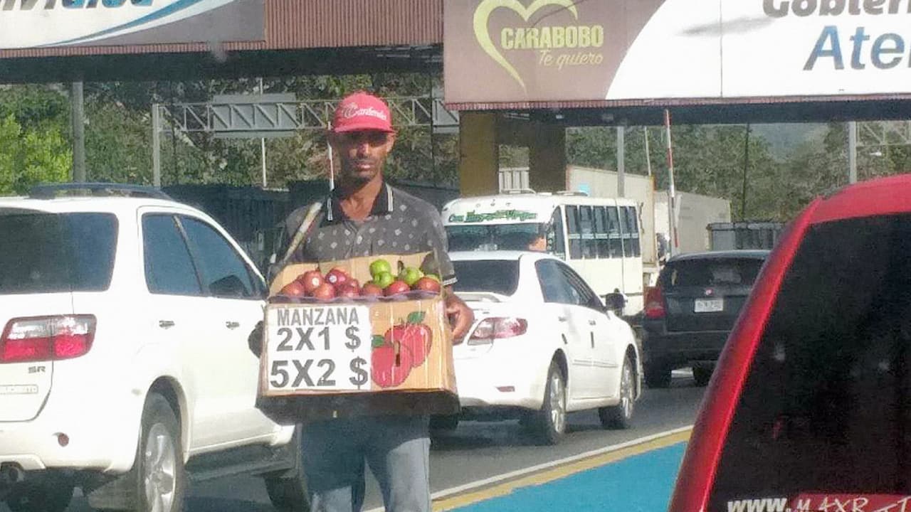 Un vendedor aprovecha el tráfico pesado de la movilización navideña para vender en dólares su producto, en el estado Carabobo, Venezuela, en pleno control cambiario.