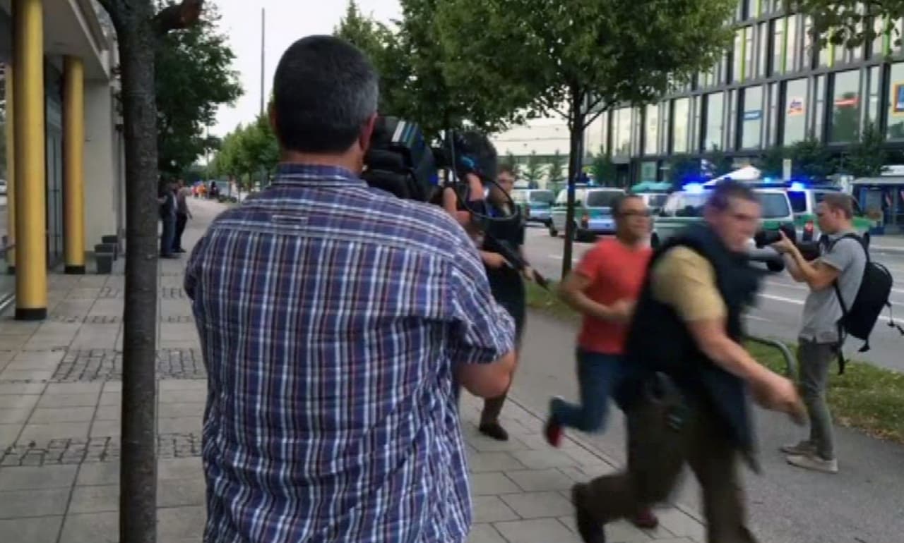 Oficiales de policía corren frente a los reporteros que cubrían el tiroteo en Münich. (AP)