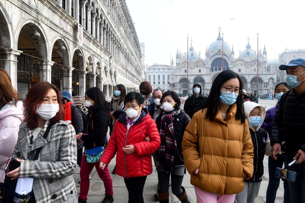 <b>Comienza la angustia en Italia (24 de febrero).</b> Turistas protegidos con máscaras en la plaza San Marco de Venecia, el día que Italia informó la cuarta muerte por covid-19. El día anterior las autoridades habían ordenado el aislamiento de 10 ciudades del norte del país, el número de casos reportados había aumentado repentinamente de menos de cinco a más de 150.