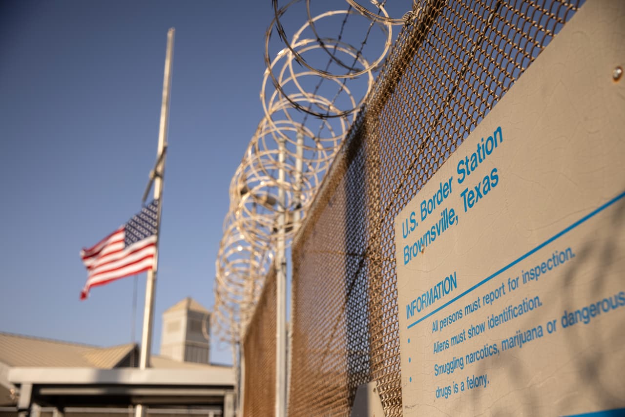 <b>Alambres y luto.</b> La bandera de Estados Unidos ondea a media asta en un puerto de entrada en la frontera entre Estados Unidos y México. El presidente de los Estados Unidos, Joe Biden, ordenó que las banderas estadounidenses en propiedad federal se ondearan a media asta durante cinco días de luto después de que Estados Unidos superara las 500,000 muertes debido al Covid-19.