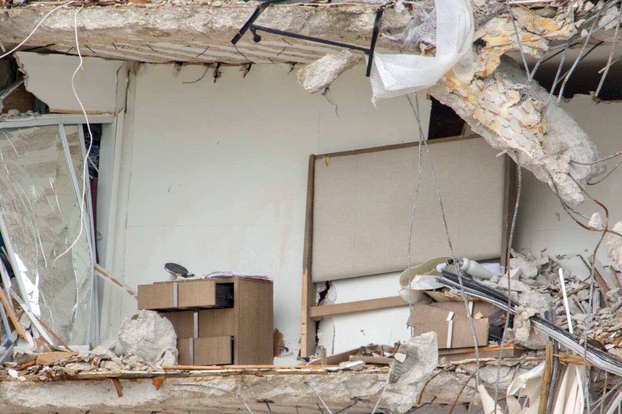 Una cabecera de cama y dos mesas de noche a cada lado en el angosto borde que dejó el derrumbe en este apartamento del piso 10. No está el colchón sobre el que probablemente alguien dormía cuando sucedió la tragedia.
<br>
<br>La ciudad de Surfside, al norte de Miami Beach, está vacía. Algunos periodistas caminan en las calles cercanas, una zona completamente cerrada por las autoridades y prácticamente en absoluto silencio. Extrañamente no hay demasiado tráfico.
<br>
