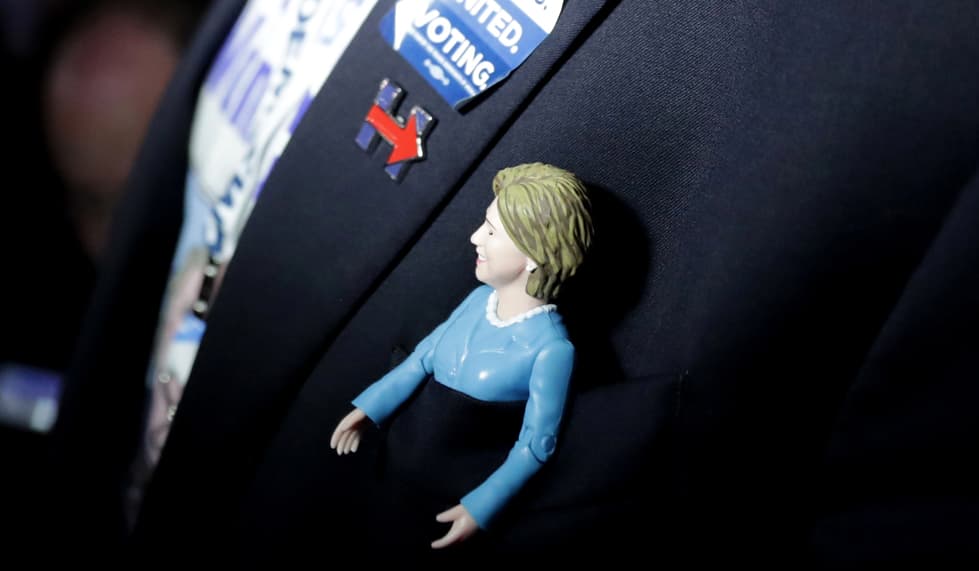 El pañuelo del bolsillo del saco de este hombre, fue desplazado por la versión miniatura de Hillary Clinton. La figura se acomodó a la perfección en este espacio.