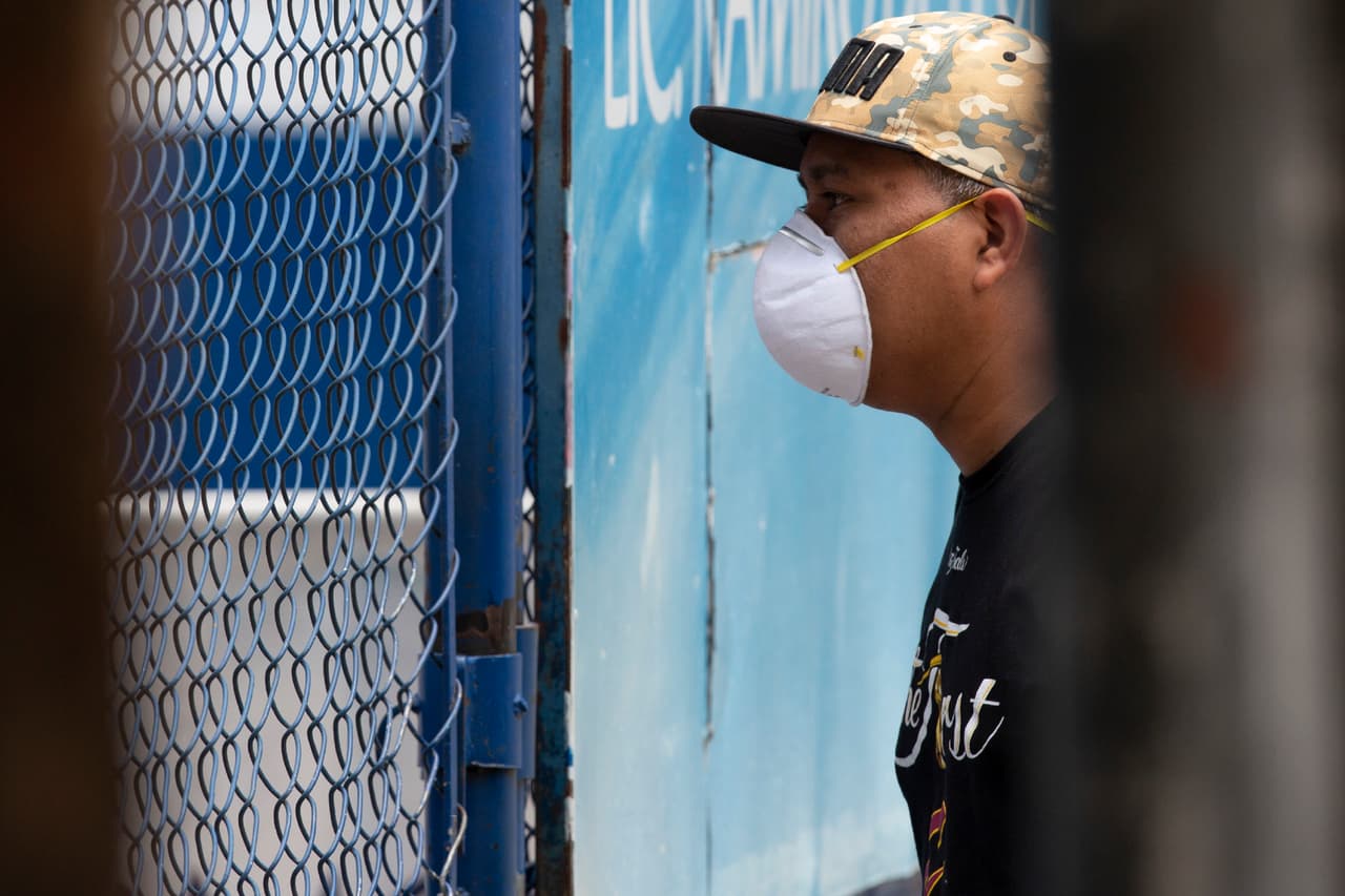 Este hombre es uno de esos familiares, que desde el lado de afuera de la cerca busca información sobre sus allegados retenidos en el refugio, que esperan el resultado de sus pruebas de coronavirus.