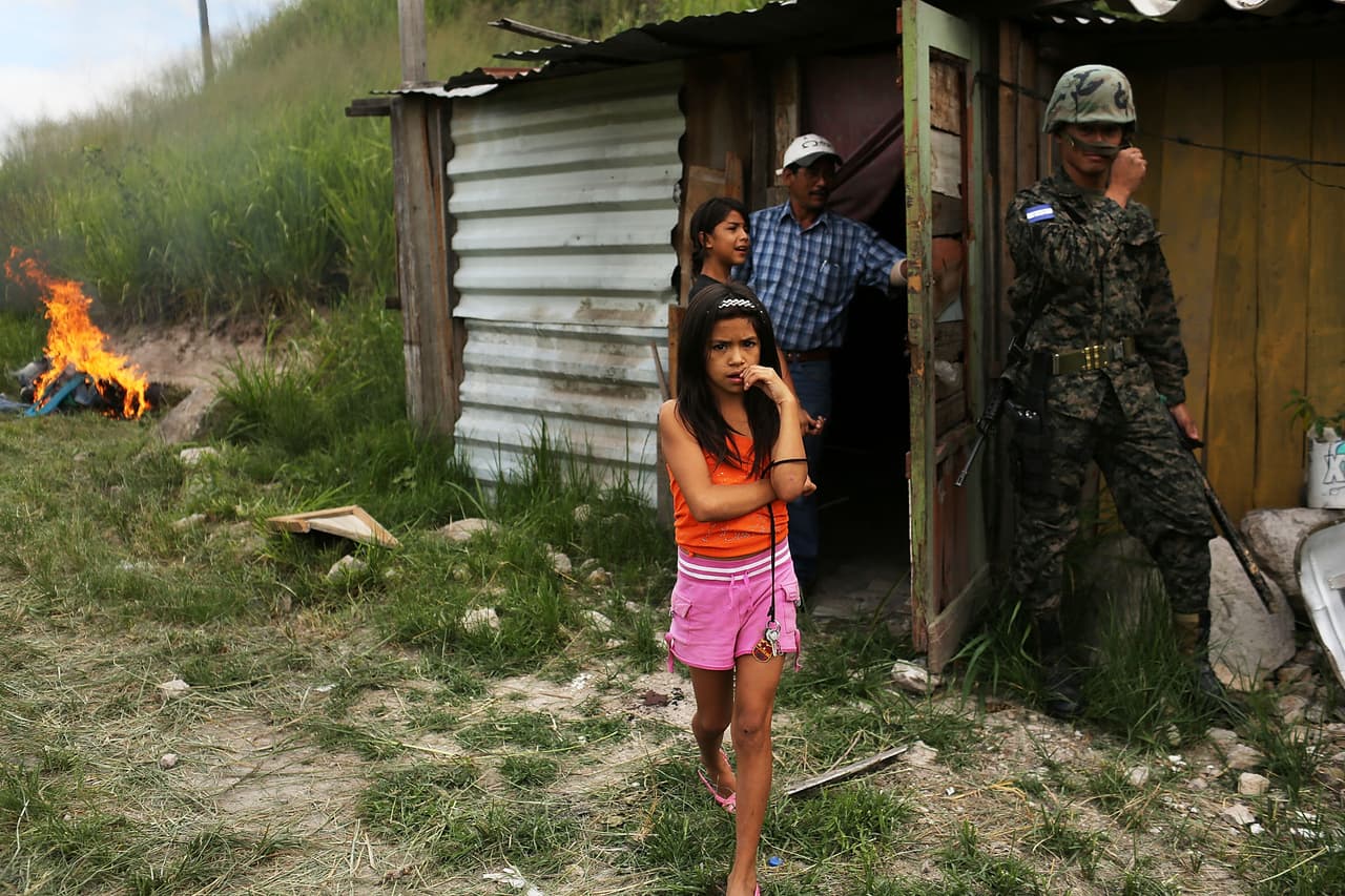 Una niña y su familia al lado de su hogar luego de que la policía y la fuerza militar los forzara a ellos y a sus vecinos a desbaratar el asentamiento luego de que el gobierno lo declarara ilegal, en julio de 2012, en Tegucigalpa, Honduras.