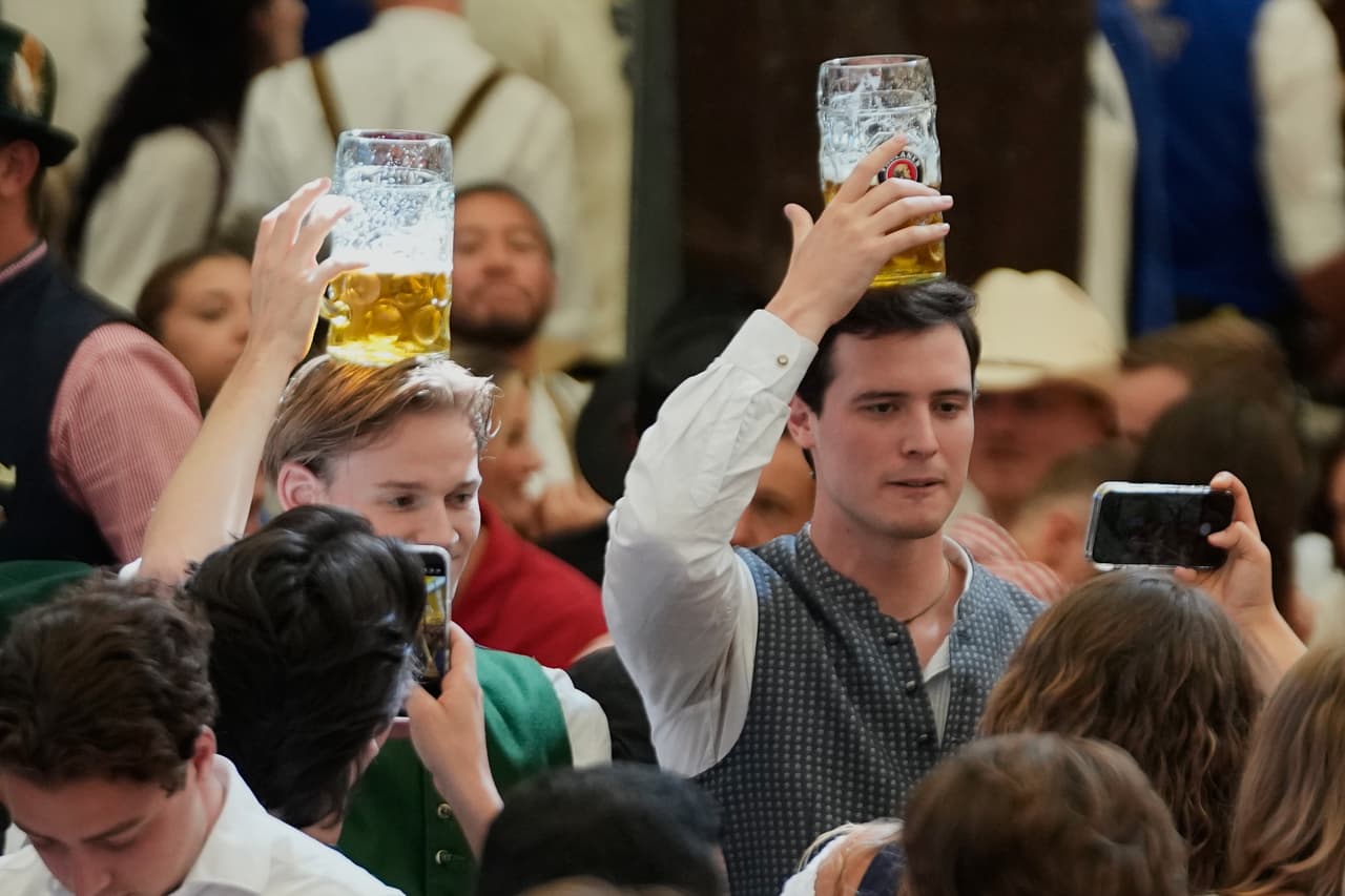 Unos visitantes llevan jarras de cerveza sobre la cabeza tras la inauguración de la 191.ª edición del festival de la cerveza Oktoberfest en Múnich, Alemania, el sábado 19 de septiembre de 2026.