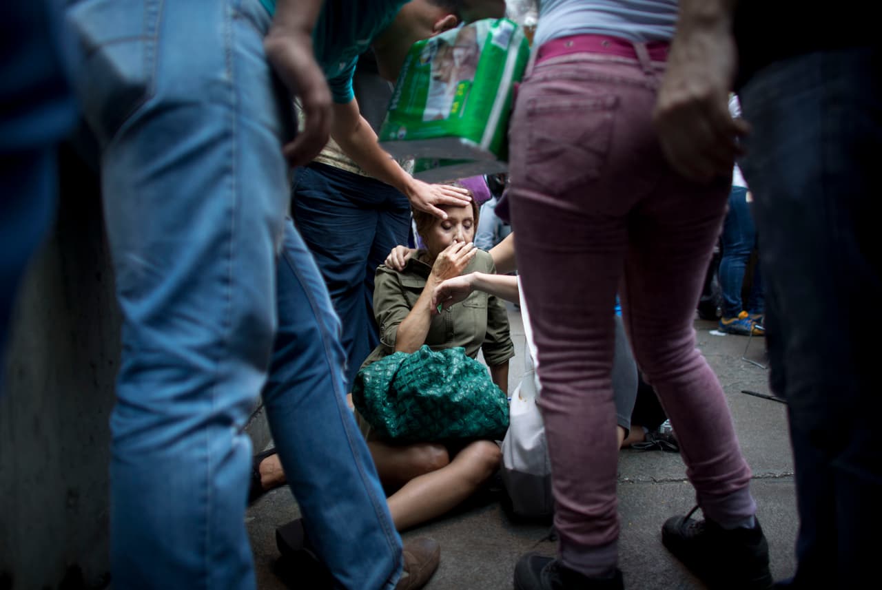 <b>Long lines</b>. To access basic products at regulated prices, Venezuelans queue for hours. In the photograph, a woman collapses after waiting in line to buy food in Caracas.
