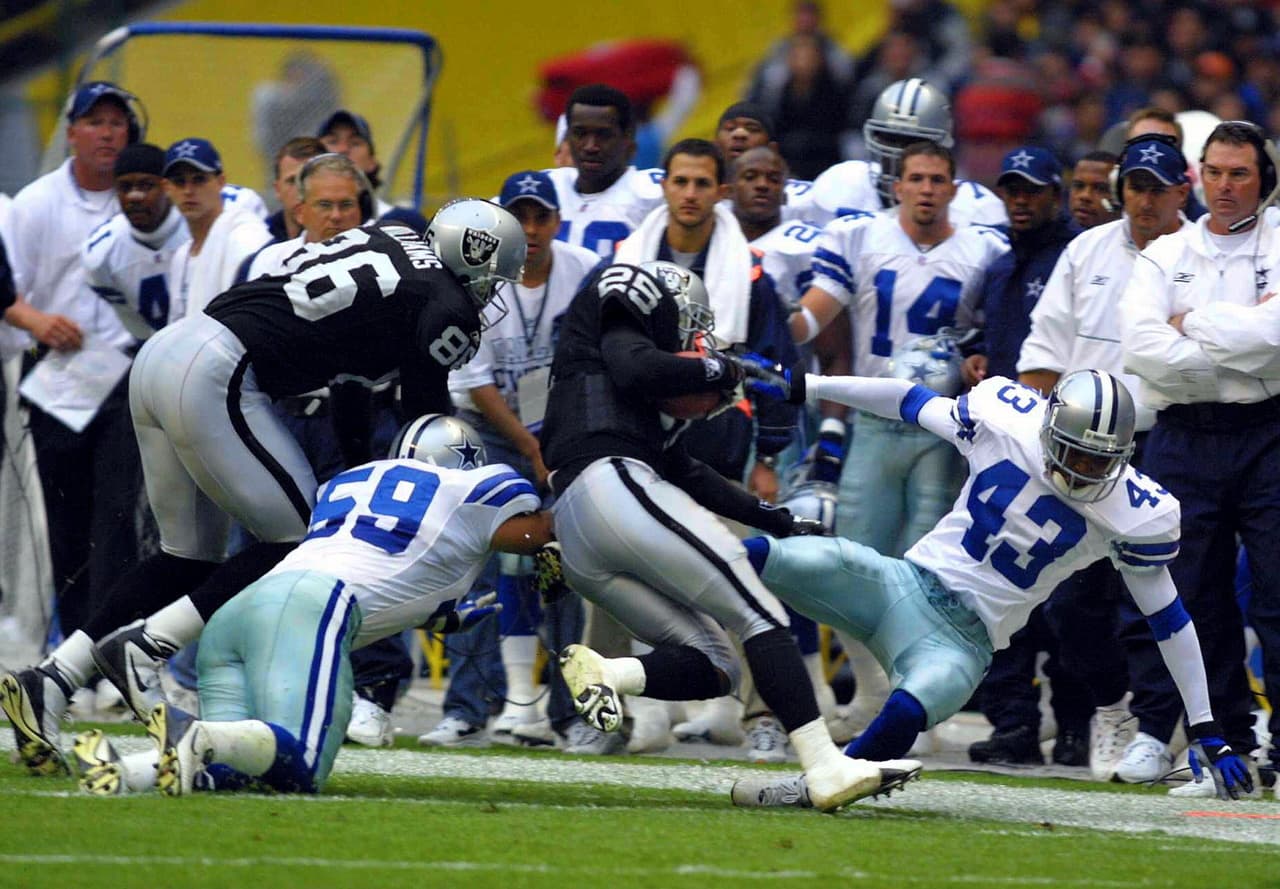 Vaya golpe que le propinó el linebacker de Dallas Dat Nguyen a Charlie Garner de Oakland. A un lado de la banca de los Cowboys se puede apreciar a Mike Zimmer (derecha), hoy con Minnesota Vikings.