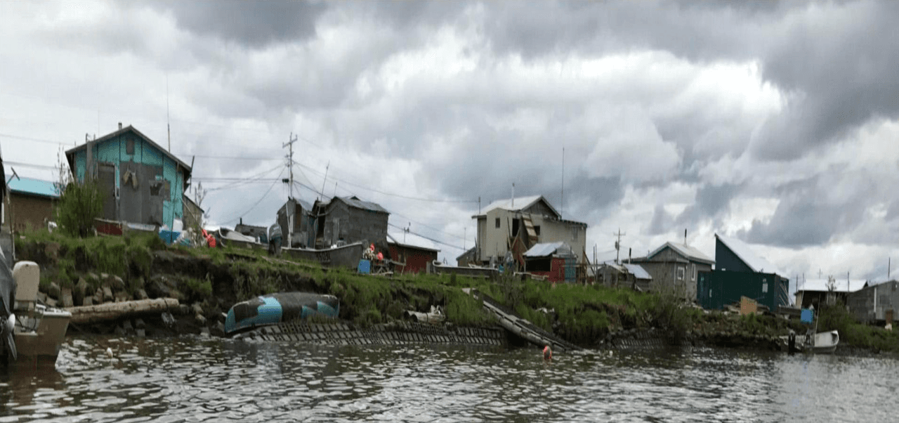 A medida que el permafrost de Alaska se derrite, socavones se han tragado casas y la erosión se ha ido comiendo las riberas. En Kotlik, Alaska, como se observa en la imagen, muchas casas y otros edificios han quedado guindando precipitosamente sobre el agua, mientras que el terreno que las sostiene va desapareciendo.